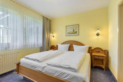a bedroom with a bed with white sheets and a window at Apartment mit Gartenblick K1 201 in Spalt