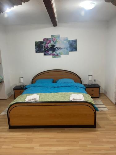 a bedroom with a bed with blue sheets and two tables at Orchidea Apartman in Bačka Topola