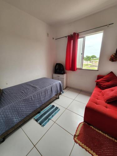 a bedroom with a bed and a red couch at Morada Aconchegante com 2 quartos and Sofá Cama in Imperatriz