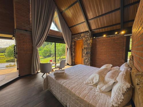 a bedroom with a large bed and a large window at Guest house Etérea in Flores da Cunha