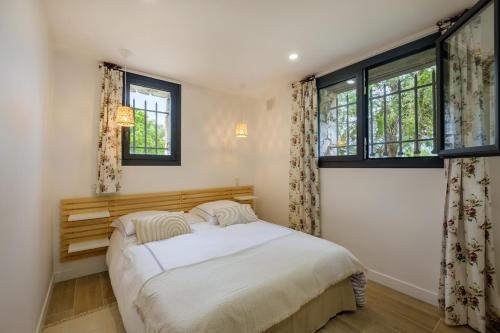a bedroom with a bed and two windows at Villa Cyprès Bleu in Peymeinade