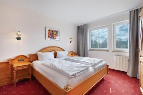 a bedroom with a bed and a nightstand and two windows at Superior Apt mit Seeblick K2 102 in Spalt