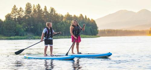 a boy and a girl on a paddle board on the water at Soda Springs Ranch Unit 3C in Grand Lake