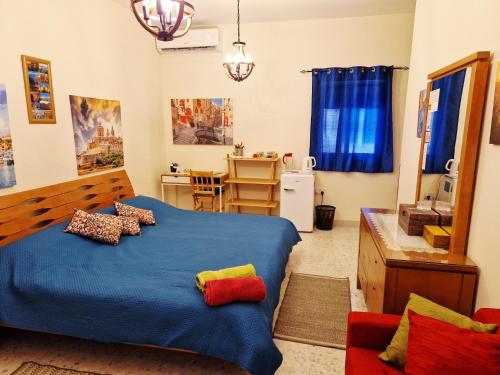 a bedroom with a blue bed and a kitchen at Saracini's Homestay in Attard