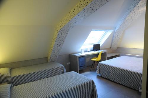 a bedroom with two beds and a desk with a computer at Hotel Astoria in Ravenna