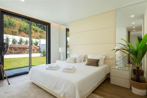a bedroom with a white bed and a large window at Casinha da Ribeira in Vila Verde