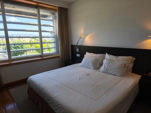 a bedroom with a large white bed with a window at Hotel Vila Luena in Vila Verde