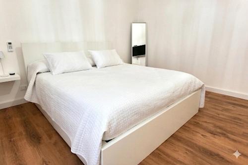 a white bed in a white bedroom with a wooden floor at La Casa Della Zia Scicli in Scicli