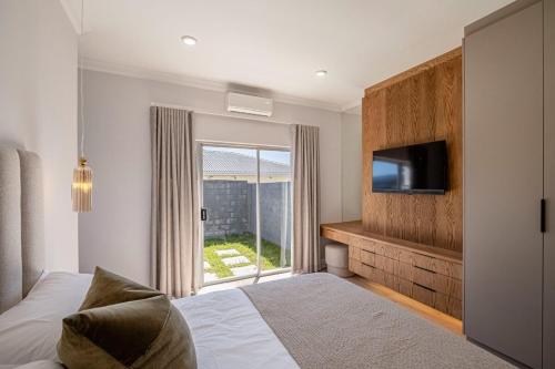 a bedroom with a bed and a tv and a window at The Shirley Too in Gqeberha