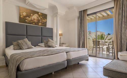 a bedroom with a large bed and a balcony at Cesar Thalasso in Midoun