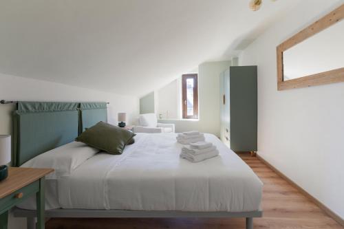 a bedroom with a large white bed with green accents at Casa Lidia in Villaretto