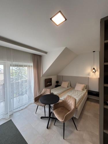 a bedroom with a bed and a table with chairs at LaMira 2,3 Apartments in Hajdúszoboszló