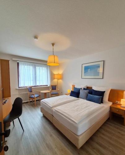 a bedroom with a large white bed and a desk at Pension Haus Weierts in Norderney