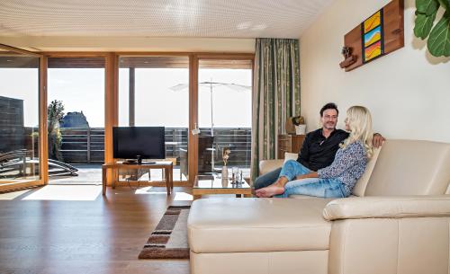 a man and woman sitting on a couch in a living room at Genusshotel Riegersburg in Riegersburg