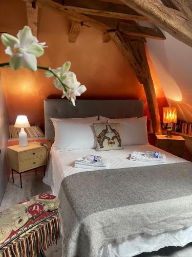 a bedroom with a bed with a vase with flowers on it at Domaine de La Vove - Maison d'hôtes classée, cadre paisible et naturel - ambiance insolite jardin paysager doté d'une terrasse spacieuse - une vue panoramique exceptionnelle -authenticité et élégance in Corbon