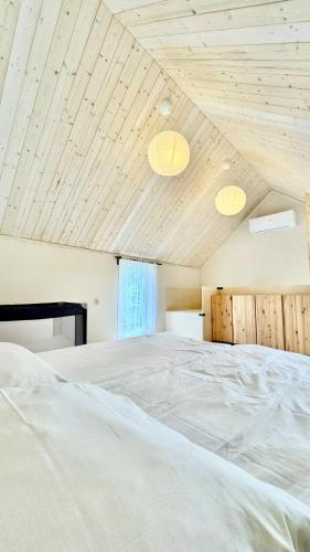 a bedroom with a large white bed with wooden ceilings at Stodoła Dębki in Dębki