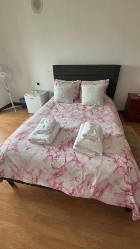a bedroom with a pink bed with two towels on it at Quarto duplo com varanda no centro de Viseu in Viseu
