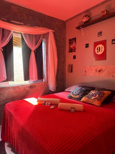 two beds in a bedroom with red sheets and a window at Suíte Harry Potter - Pousada Castelo do Luar in Penha