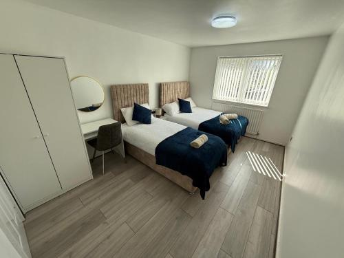 a bedroom with two beds and a desk with a mirror at The cumbria place in Elswick
