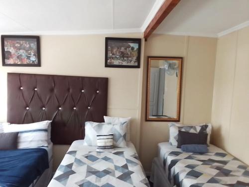 a bedroom with two beds and a mirror at MOFFAT GUEST HOUSE in Randfontein