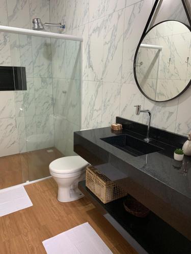 a bathroom with a toilet and a sink and a mirror at Casa Por Do Sol in Paraty