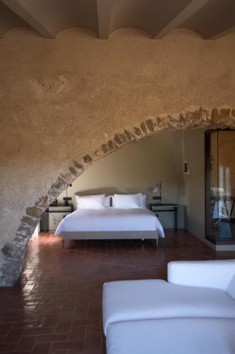 a bedroom with a white bed in a stone wall at Hotel la Plaça Madremanya in Madremanya