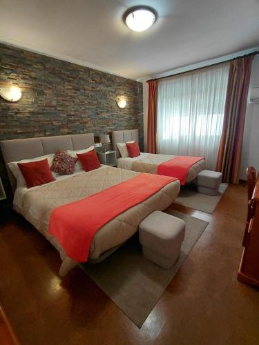 a bedroom with two beds and a brick wall at Hotel Santa Apolonia in Bragança