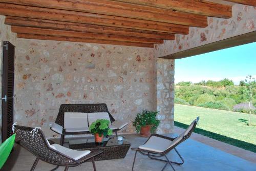 a patio with chairs and a table and a stone wall at Luxury Villa Son Mas in Manacor