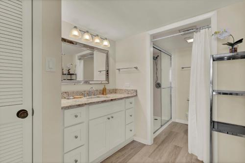 a white bathroom with a sink and a mirror at Station One - 6K by Sea Scape Properties in Wrightsville Beach