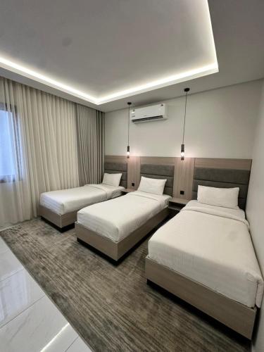 two beds in a hotel room with white sheets at Bee House in Taif
