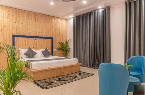 a bedroom with a bed and some blue chairs at Silver Crest Hotel Kasauli in Kasauli