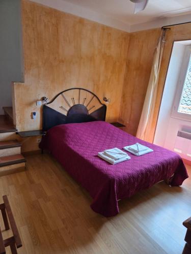 a bedroom with a purple bed with two towels on it at Hotel Des Sites in Salavas