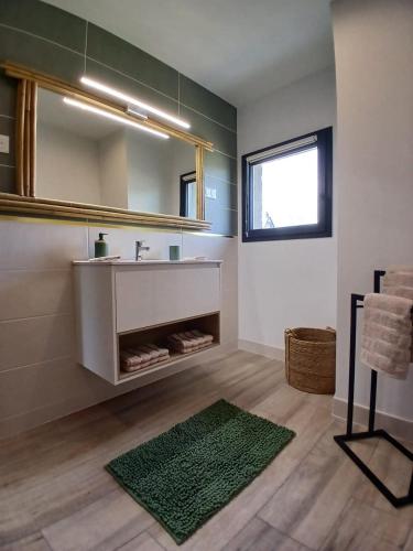 a bathroom with a sink and a mirror and a rug at Maison en Auvergne - Chez Julien et Stephy in Celles