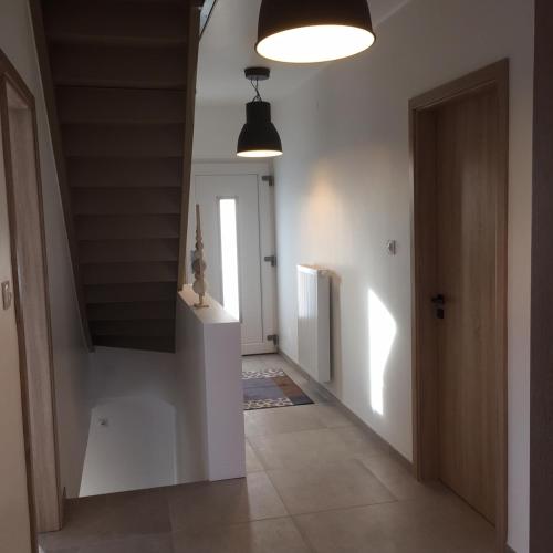 un couloir aux murs blancs et un escalier avec deux lumières dans l'établissement La Clé Des Vignes, à Ribeauvillé