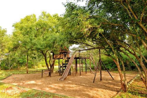 a playground with a slide in a park with trees at Musangano Lodge in Odzi