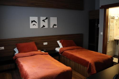 a bedroom with two beds with orange comforters at Prior Hotel in Prizren