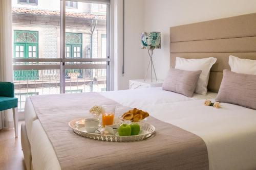 Una cama con una bandeja de comida encima en Simon Guest Apartments, en Oporto