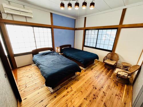 a bedroom with two beds and a wooden floor at K'sVILLAGE 平砂浦ハウスＳ in Tateyama