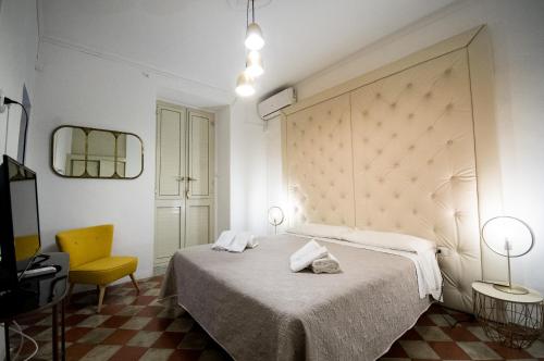 a bedroom with a bed and a yellow chair at BIANCA ROOMS in Noto