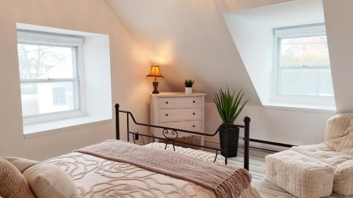 a bedroom with a bed and a dresser and two windows at Maison meublée et équipée, clé en main pour séjours 31 jours et plus! in Quebec City