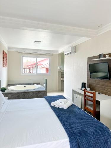 a bedroom with a bed and a bath tub at Hotel Geranius Ingleses in Florianópolis