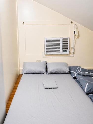 a room with a bed with a air conditioner on the wall at Affordable MODERN Up to 16 Pax Near Aqua Planet & Clark International Airport in Angeles