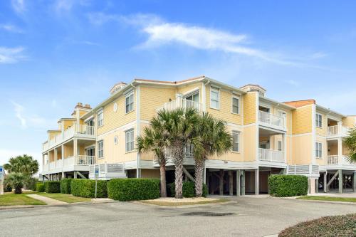 a large apartment building with palm trees in front at Dreamer by Oak Island Accommodations in Oak Island