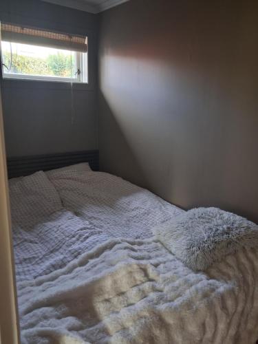 an unmade bed in a bedroom with a window at Leilighet i Lyngdal in Lyngdal