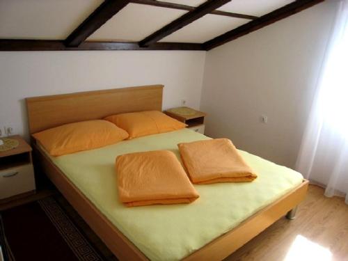 1 dormitorio con 1 cama con sábanas y almohadas de color naranja en Apartments Karuso, en Kampor