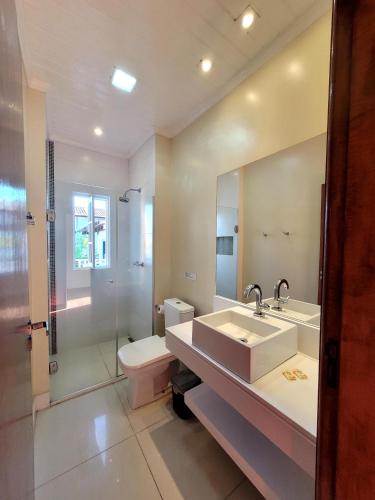 a bathroom with a sink and a toilet and a mirror at Pousada Casa Hospedaria in Paraty