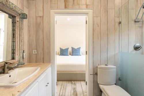 a bathroom with a sink and a toilet and a bed at Casa Pôr do Sal - Boutique Suites, Sea Views & Heated Pool in Luz