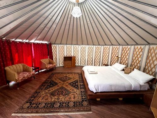a bedroom in a yurt with a bed and two chairs at Moksha Resort Hunza in Chamangul