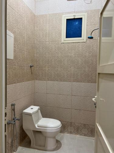 a small bathroom with a toilet and a window at شادن للوحدات السكنية in Qufār