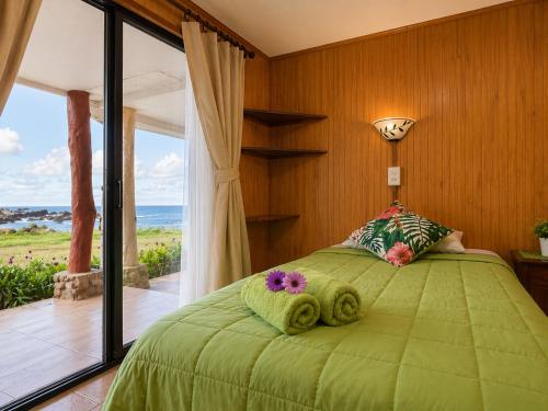 a bedroom with a green bed with a view of the ocean at Cabañas & Hostal Tojika in Hanga Roa